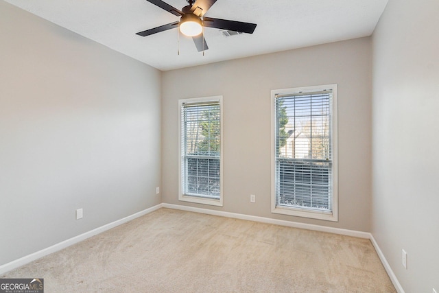 empty room featuring a ceiling fan, light colored carpet, and baseboards