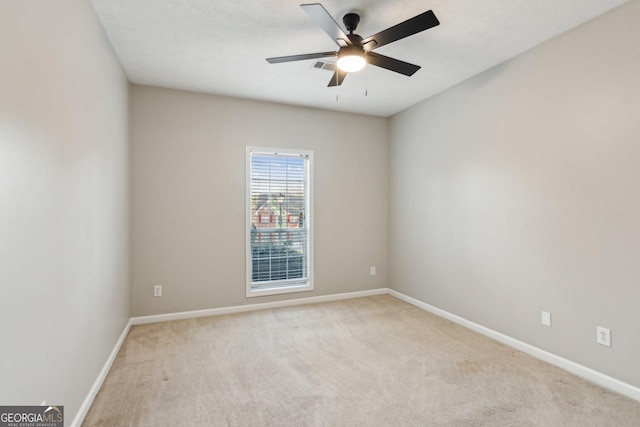 empty room with light carpet, a ceiling fan, and baseboards