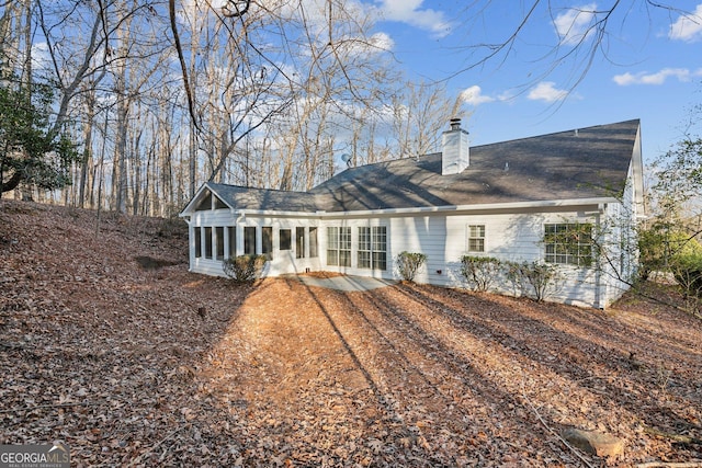 back of house with a sunroom and a chimney