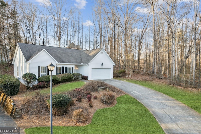 ranch-style house with a garage, driveway, roof with shingles, and a front yard