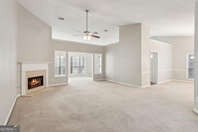 unfurnished living room featuring light carpet, plenty of natural light, a fireplace, and visible vents