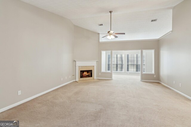 unfurnished living room with light colored carpet, visible vents, a ceiling fan, a high end fireplace, and baseboards