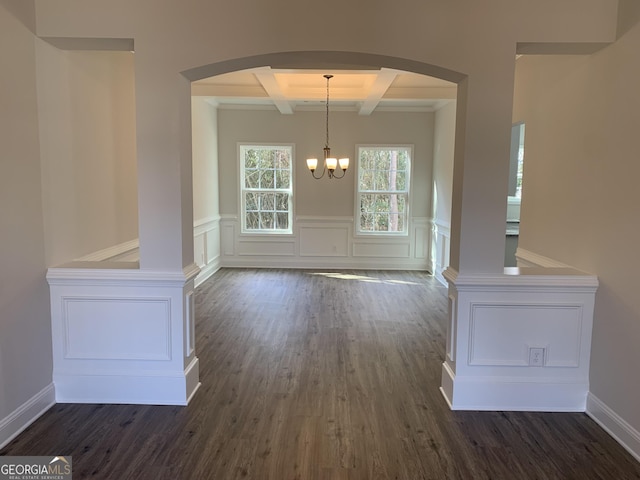 unfurnished dining area featuring beamed ceiling, coffered ceiling, dark wood-type flooring, and an inviting chandelier