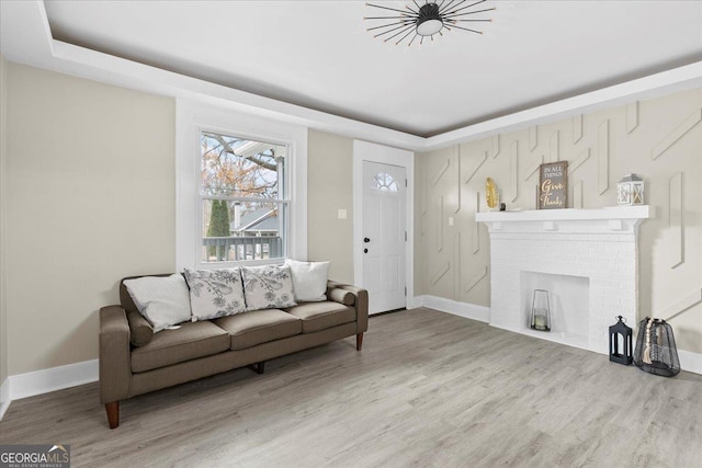 living room with a raised ceiling, wood-type flooring, and a fireplace