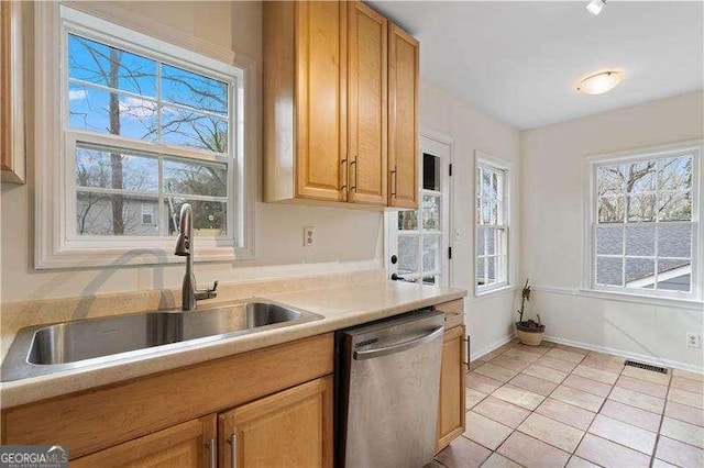 kitchen featuring stainless steel dishwasher, sink, and light tile patterned floors