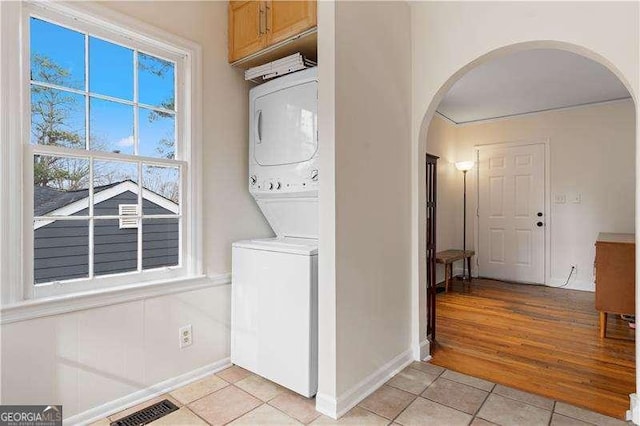 washroom featuring light tile patterned flooring and stacked washer / dryer