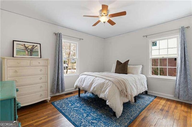 bedroom featuring multiple windows, dark wood-type flooring, and ceiling fan