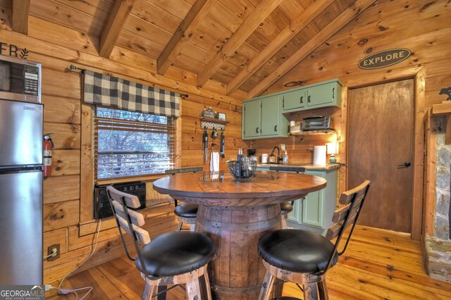 kitchen featuring light hardwood / wood-style flooring, appliances with stainless steel finishes, vaulted ceiling with beams, green cabinetry, and wooden ceiling