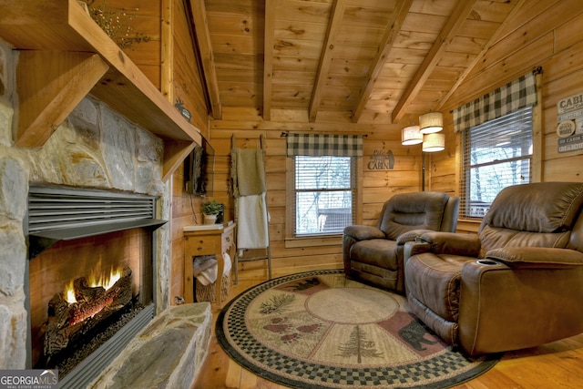 living area featuring wooden walls, vaulted ceiling with beams, wood ceiling, and a warm lit fireplace