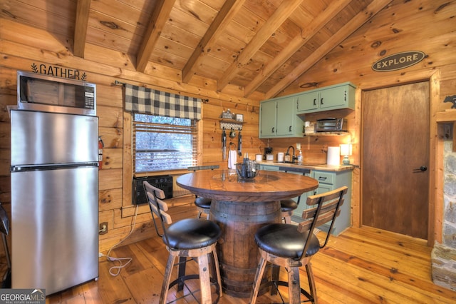 kitchen featuring vaulted ceiling with beams, green cabinets, stainless steel appliances, wooden ceiling, and light wood-type flooring