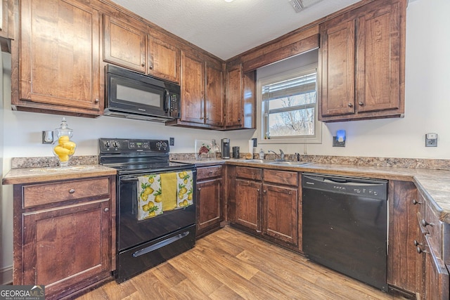 kitchen with a textured ceiling, sink, light hardwood / wood-style flooring, and black appliances