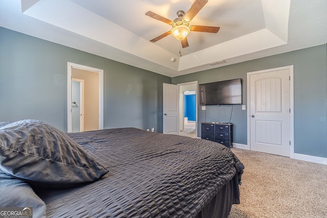 bedroom with a raised ceiling, carpet floors, and ceiling fan