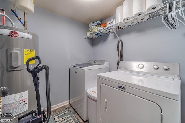 clothes washing area featuring washing machine and dryer, water heater, and a textured ceiling