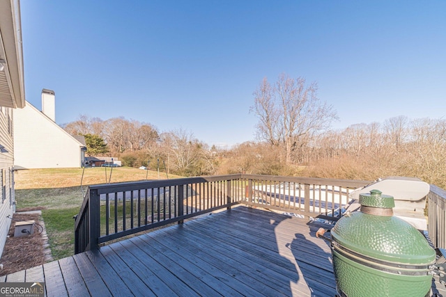 wooden terrace featuring a grill and a lawn