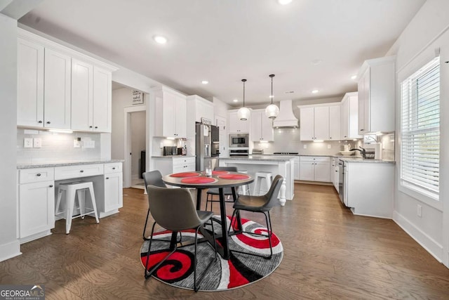 kitchen featuring a kitchen island, pendant lighting, white cabinetry, stainless steel appliances, and custom range hood