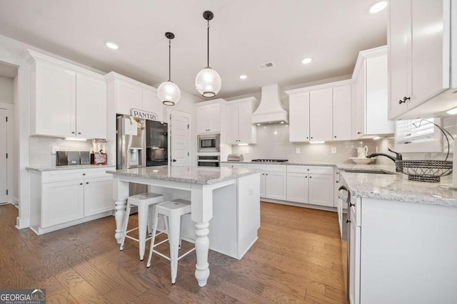 kitchen featuring stainless steel appliances, premium range hood, and white cabinetry