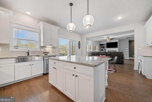 kitchen featuring sink, dark wood-type flooring, white cabinetry, hanging light fixtures, and stainless steel dishwasher