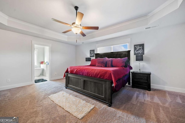 bedroom featuring a tray ceiling, ensuite bath, ornamental molding, and ceiling fan