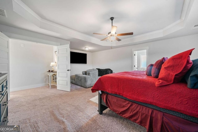 carpeted bedroom with crown molding, a tray ceiling, and ceiling fan