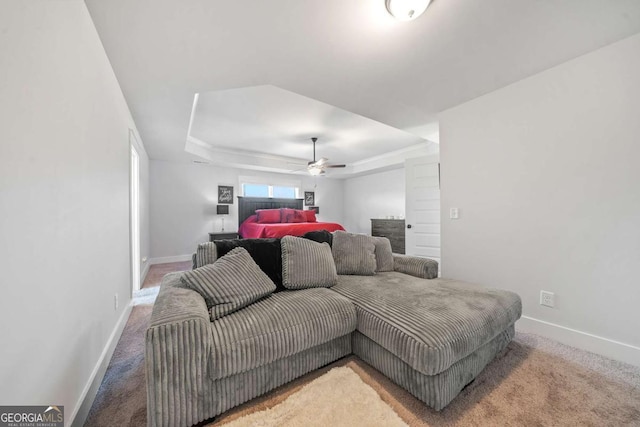 carpeted bedroom featuring ceiling fan and a tray ceiling