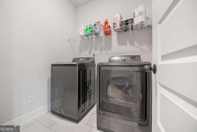 laundry area with washer and clothes dryer and light tile patterned flooring