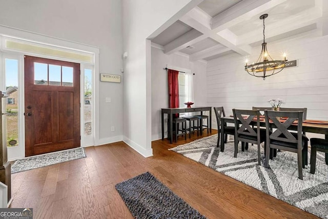 foyer with beamed ceiling, coffered ceiling, dark wood-type flooring, and a notable chandelier