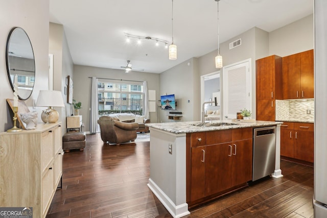 kitchen with sink, dishwasher, an island with sink, pendant lighting, and backsplash