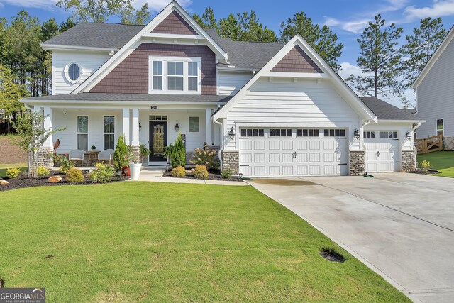 craftsman-style home with a garage, a front yard, and covered porch