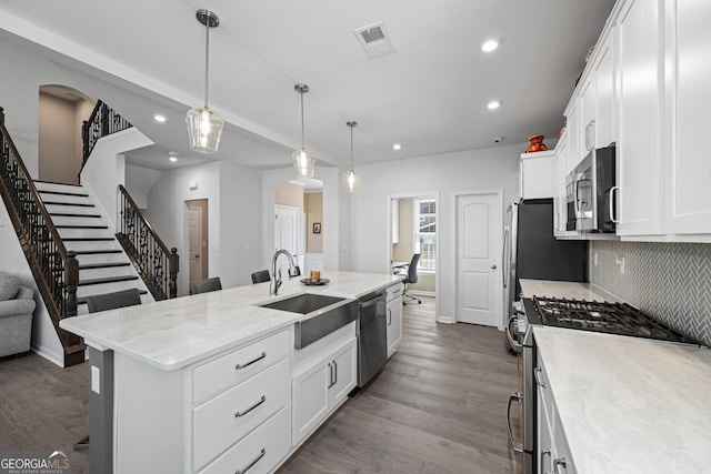 kitchen featuring pendant lighting, sink, a kitchen island with sink, stainless steel appliances, and white cabinets