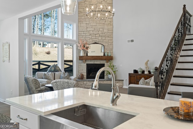 kitchen with a fireplace, decorative light fixtures, sink, a high ceiling, and hardwood / wood-style flooring