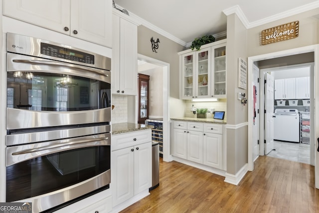 kitchen featuring stainless steel double oven, light stone countertops, and white cabinets