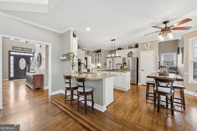 kitchen with pendant lighting, white cabinetry, sink, stainless steel appliances, and crown molding