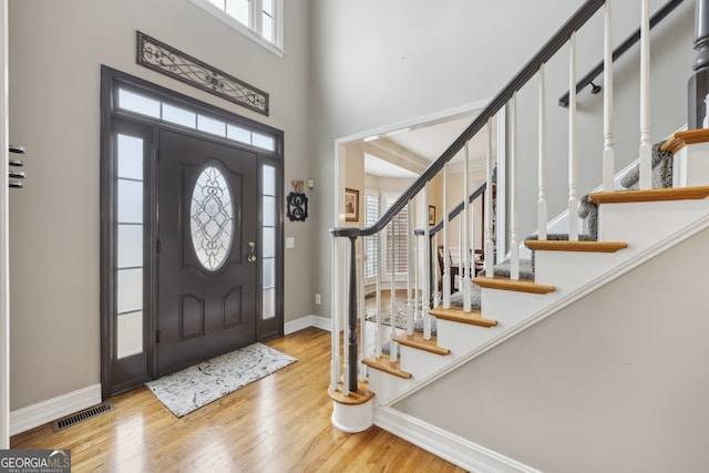 entrance foyer featuring a towering ceiling and light hardwood / wood-style floors