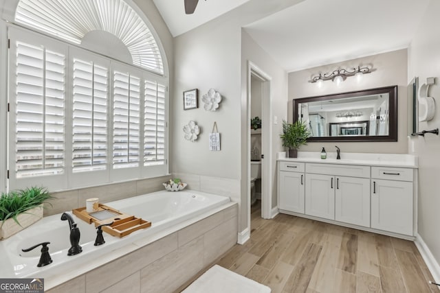 bathroom featuring lofted ceiling, toilet, vanity, hardwood / wood-style flooring, and tiled bath