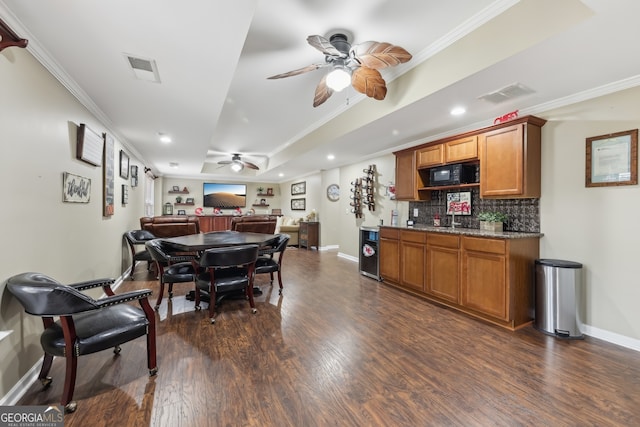 dining area featuring crown molding, indoor bar, dark hardwood / wood-style flooring, and ceiling fan