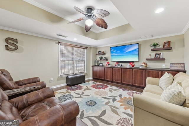 living room featuring a raised ceiling, crown molding, light wood-type flooring, and ceiling fan