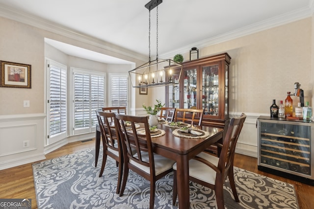 dining area with dark wood-type flooring, beverage cooler, and crown molding