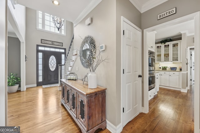 foyer with light hardwood / wood-style flooring and ornamental molding