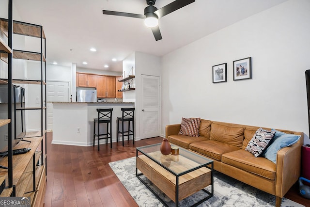 living room featuring dark wood-type flooring and ceiling fan