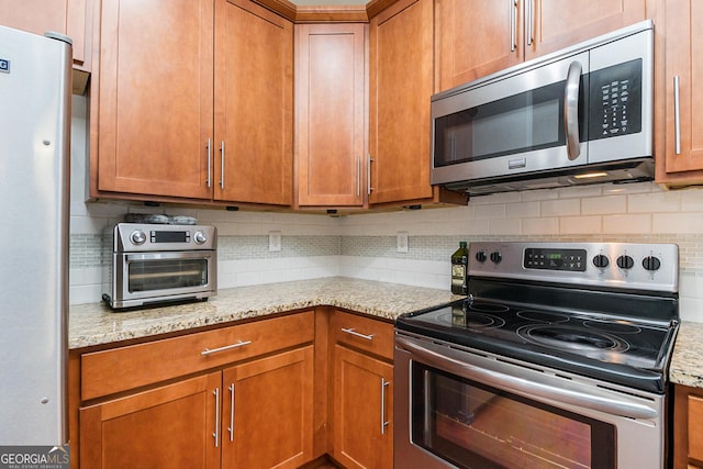 kitchen with tasteful backsplash, light stone counters, and stainless steel appliances