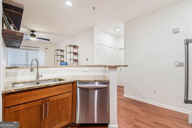 kitchen featuring dishwasher, sink, ceiling fan, light stone counters, and light hardwood / wood-style flooring