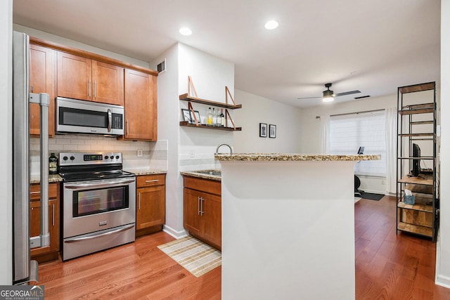 kitchen featuring light hardwood / wood-style floors, stainless steel appliances, kitchen peninsula, and sink