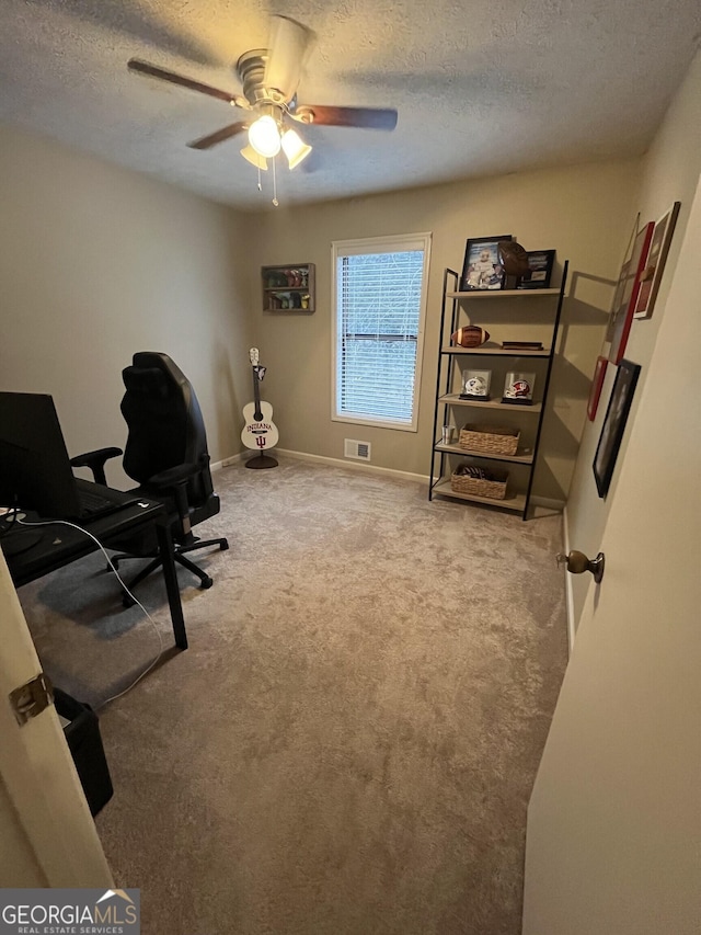 home office with ceiling fan, a textured ceiling, and carpet