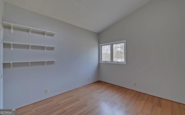 empty room with vaulted ceiling and light hardwood / wood-style flooring