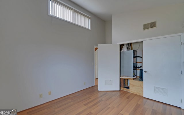 unfurnished bedroom featuring light hardwood / wood-style floors and a high ceiling