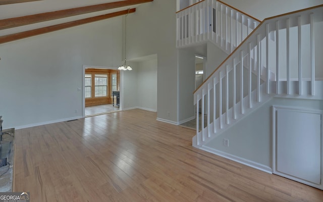 unfurnished living room featuring a notable chandelier, high vaulted ceiling, and light hardwood / wood-style flooring