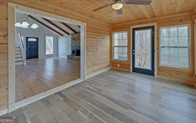 entrance foyer with plenty of natural light, wood-type flooring, lofted ceiling with beams, and wood walls