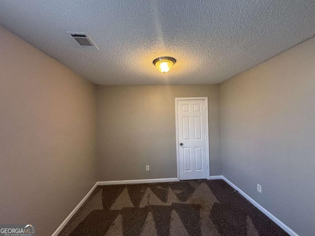 carpeted empty room featuring a textured ceiling