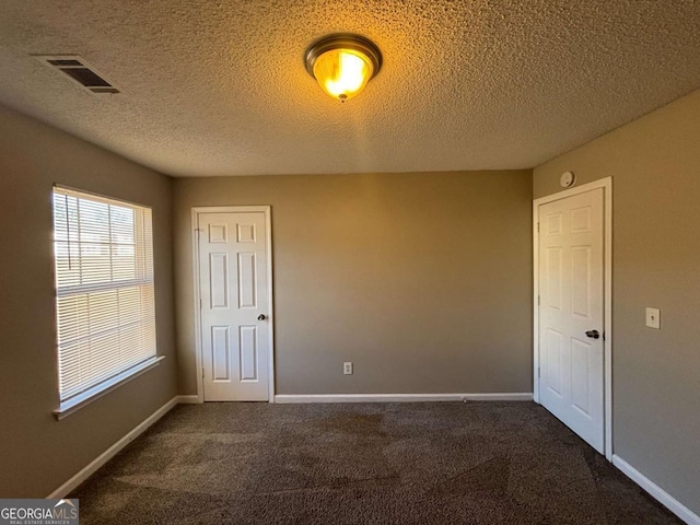 carpeted empty room featuring a textured ceiling