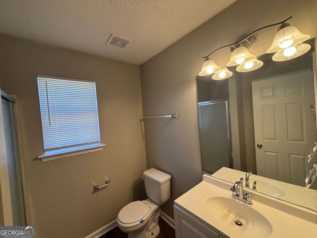 bathroom with an enclosed shower, vanity, toilet, and a textured ceiling